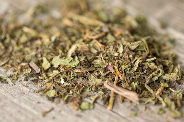 Kopje biologische paardenbloemblad thee met gedroogde groene bladeren