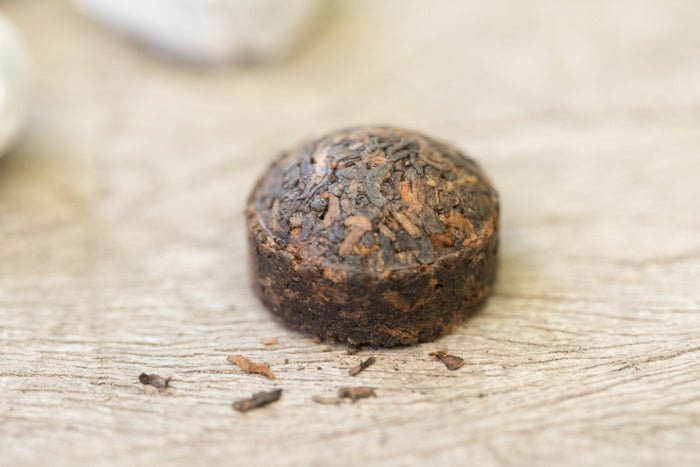 Pu-erh theecake uit Yunnan met losse bladeren en een warme, aardse infusie
