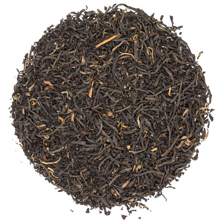 Een ronde hoop Colombia La Cumbre Valle del Cauca Sweet Ruby biologische losse thee, donker met lichtere stukjes, op een witte ondergrond.