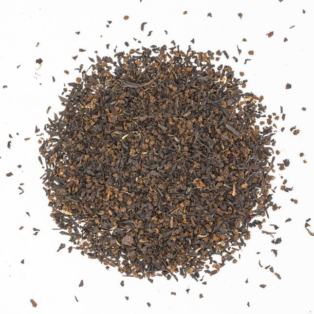 Losse biologische English Breakfast thee van De Theeplantage ligt in een cirkel op een witte ondergrond, met wat kleine stukjes eromheen.