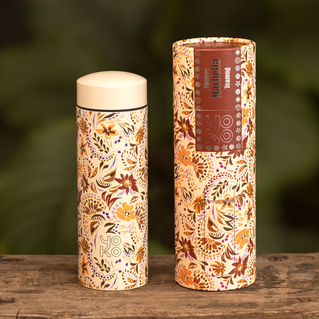 Yoko Design geïsoleerde drinkfles Marbella 350 ml en de bijpassende koker met bloemenmotief staan op hout, groene achtergrond vaag.