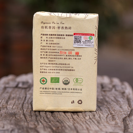 Pu-erh Shu Bio Wu Liang Legend 2015 losse thee van De Theeplantage, biologisch verpakt met Chinese tekst en keurmerken op houten ondergrond.