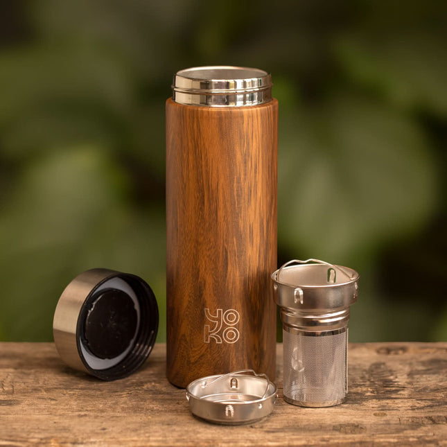 Dubbelwandige Yoko Design theepot van 350 ml op hout, met losse metalen zeefonderdelen, label YOKO en groene achtergrond.
