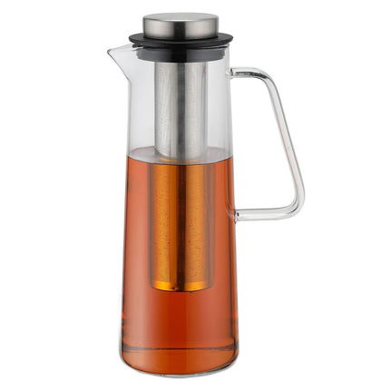Een glazen Karl Weis karaf van 1 liter met een diep rvs filter en halfgevuld met amberkleurige losse thee, het handvat rechts.